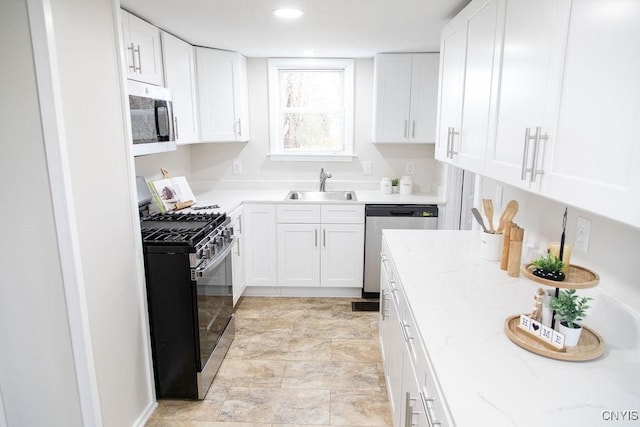 kitchen featuring a sink, light stone counters, stone finish floor, white cabinetry, and appliances with stainless steel finishes