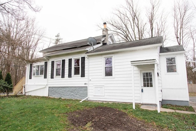 view of side of home with a chimney and a yard