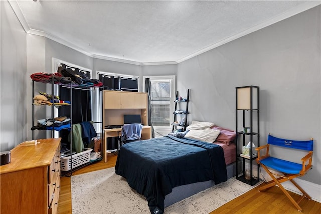 bedroom with ornamental molding and light wood finished floors