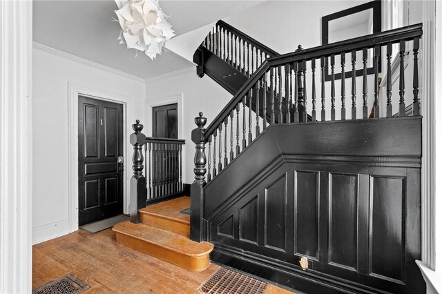 entrance foyer with stairway, crown molding, visible vents, baseboards, and wood finished floors