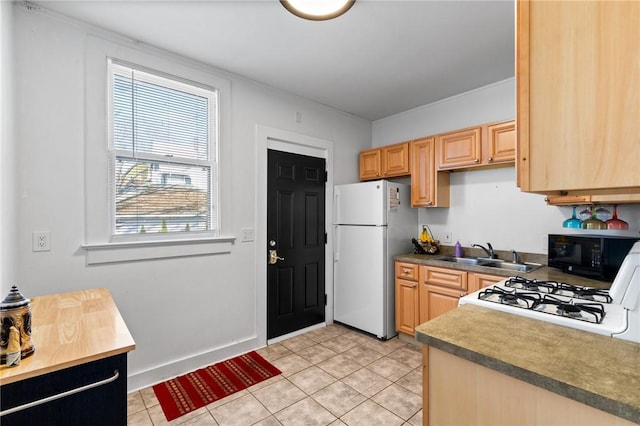 kitchen featuring a sink, light tile patterned flooring, black microwave, range with gas cooktop, and freestanding refrigerator