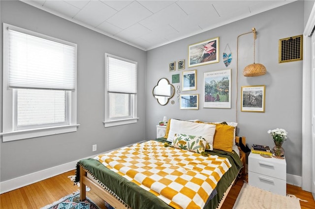 bedroom with baseboards, visible vents, and wood finished floors