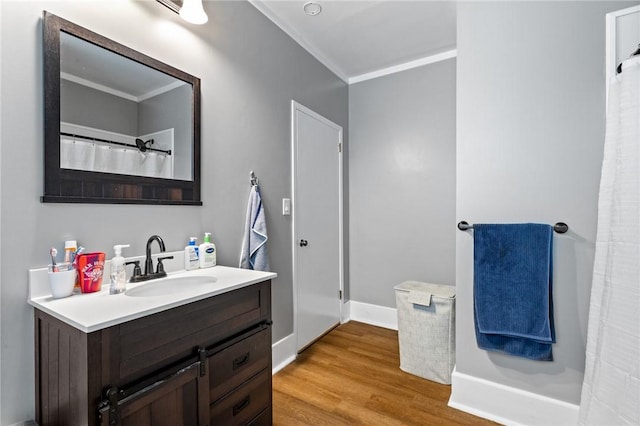 full bathroom featuring baseboards, wood finished floors, ornamental molding, and vanity