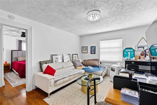living room featuring a textured ceiling, a notable chandelier, and wood finished floors