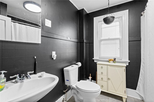 bathroom with a shower with curtain, tile walls, a sink, toilet, and ornamental molding