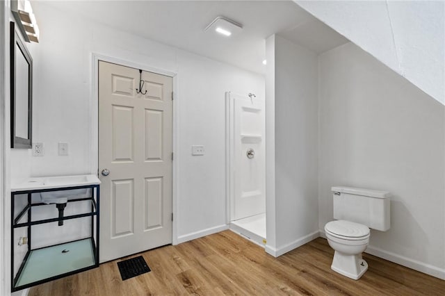 full bathroom with toilet, a stall shower, wood finished floors, and baseboards