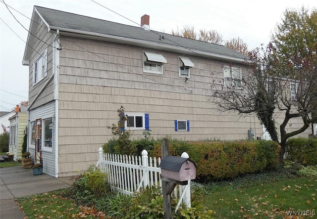 view of side of property featuring a chimney and fence