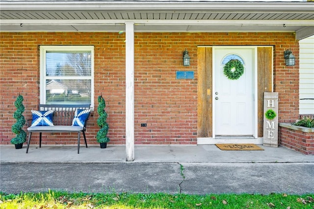 entrance to property with a porch and brick siding