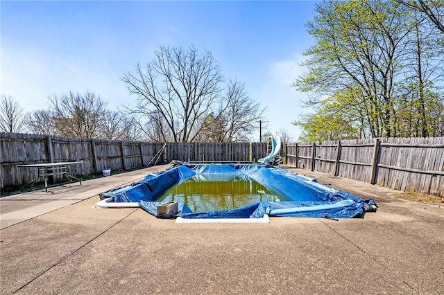 view of swimming pool with a water slide, a fenced backyard, a fenced in pool, and a patio area