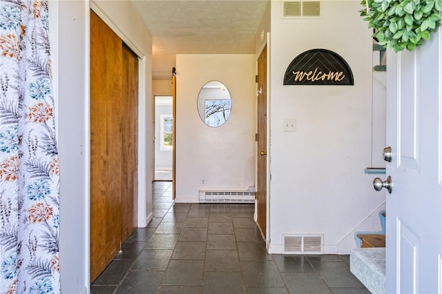 interior space with visible vents, baseboards, stone tile flooring, and a baseboard radiator