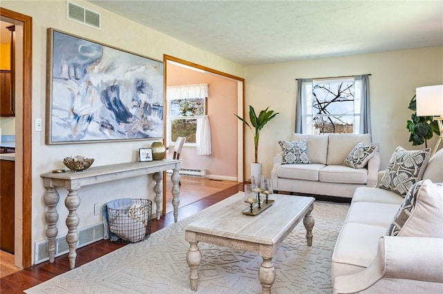living area featuring visible vents, baseboards, wood finished floors, and a baseboard radiator