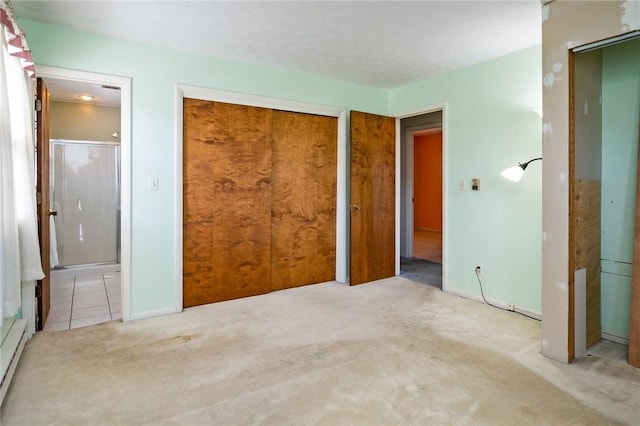 unfurnished bedroom featuring carpet, baseboards, tile patterned flooring, baseboard heating, and ensuite bathroom