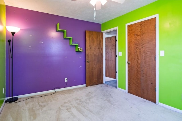 unfurnished bedroom featuring a textured ceiling, a closet, baseboards, carpet, and a ceiling fan