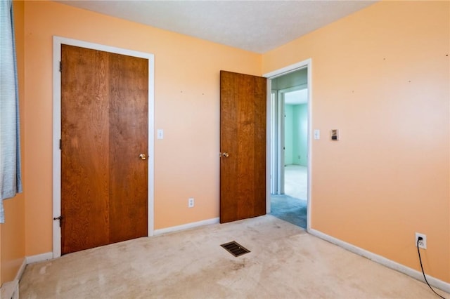 unfurnished bedroom with visible vents, carpet, and baseboards