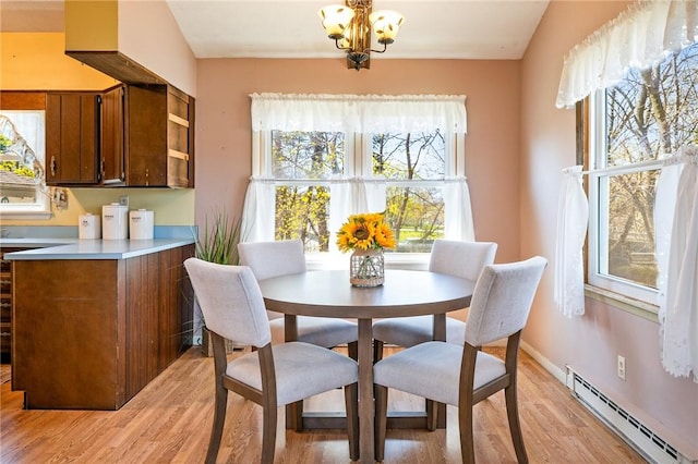 dining area featuring light wood-style floors, a notable chandelier, and a baseboard heating unit