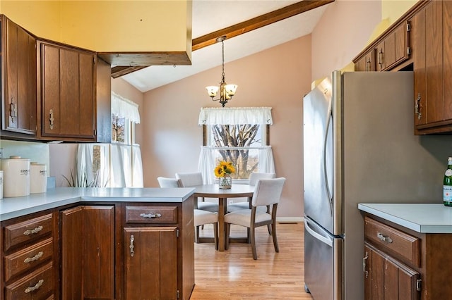 kitchen featuring light wood finished floors, a chandelier, vaulted ceiling with beams, light countertops, and freestanding refrigerator