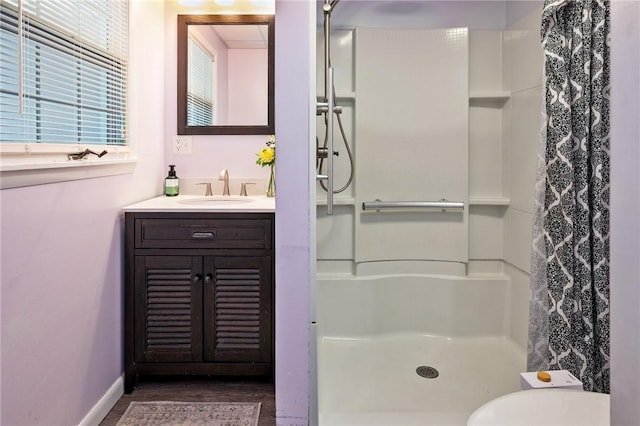 bathroom with baseboards, a stall shower, wood finished floors, and vanity