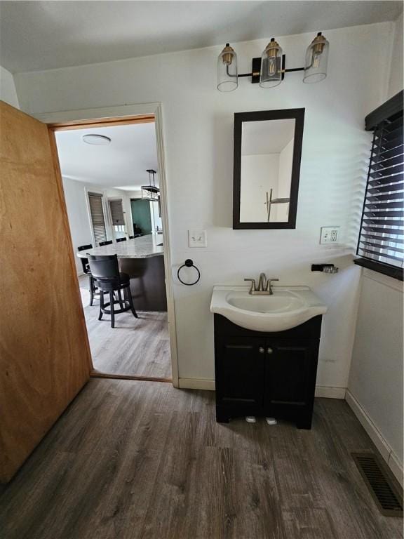 bathroom featuring wood finished floors, vanity, visible vents, and baseboards