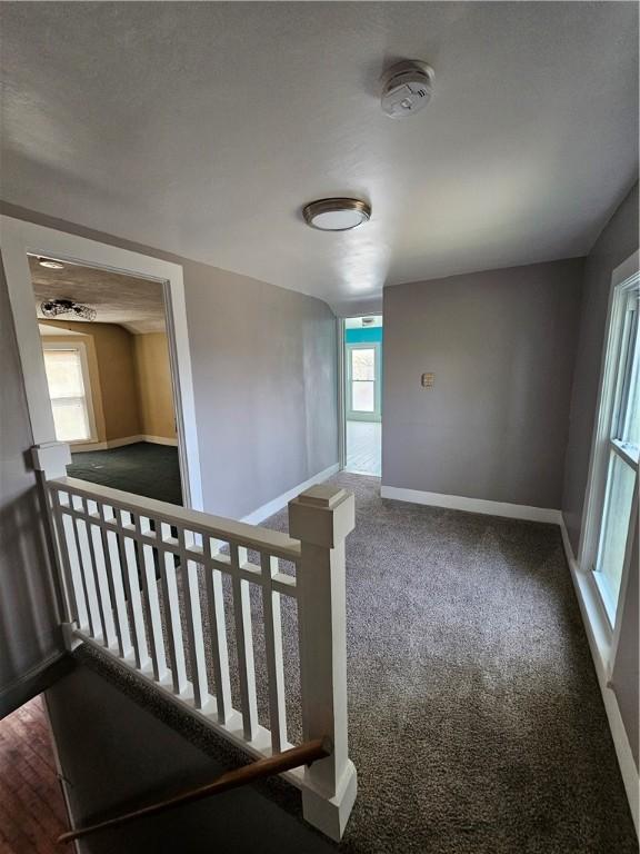 interior space featuring an upstairs landing, carpet flooring, and baseboards