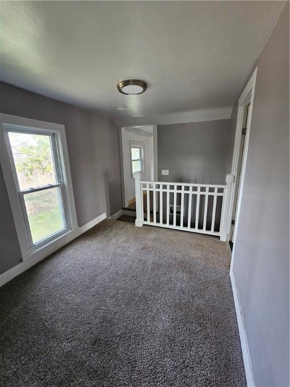 spare room featuring carpet flooring and baseboards