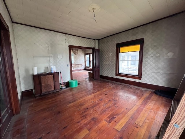 spare room with ornamental molding, baseboards, wallpapered walls, and wood-type flooring