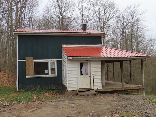 view of front of home with entry steps, a carport, and metal roof