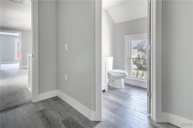 hallway featuring lofted ceiling, dark wood-style flooring, and baseboards
