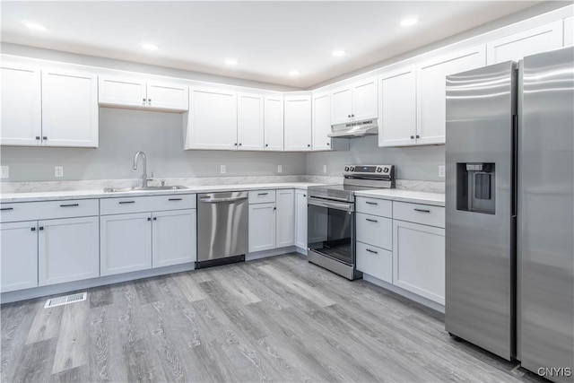 kitchen with a sink, under cabinet range hood, visible vents, light countertops, and appliances with stainless steel finishes