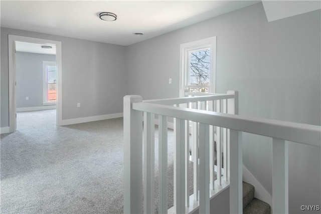 hall with baseboards, an upstairs landing, and carpet