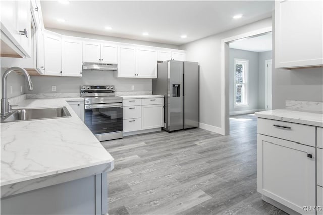 kitchen featuring a sink, appliances with stainless steel finishes, under cabinet range hood, and light wood-style floors