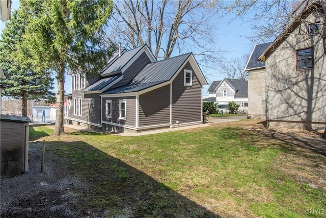 rear view of property with metal roof and a yard