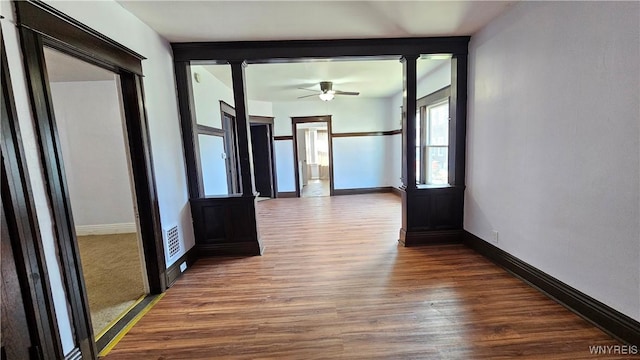 hallway featuring baseboards, visible vents, and wood finished floors