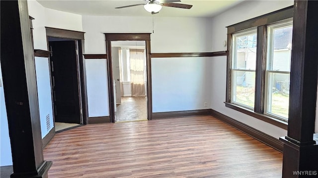 empty room featuring baseboards, wood finished floors, and a ceiling fan