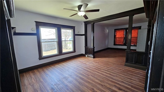 empty room with ceiling fan, baseboards, and dark wood finished floors