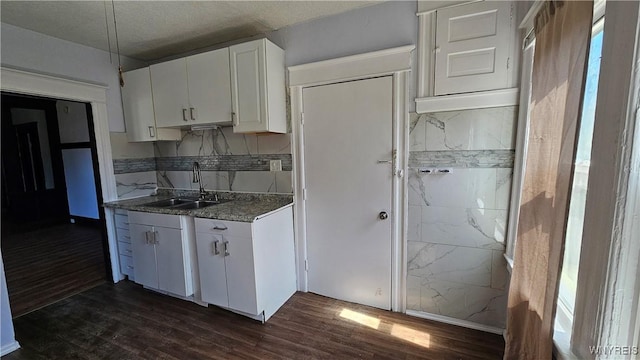 kitchen featuring a sink, white cabinets, tasteful backsplash, and dark wood-type flooring