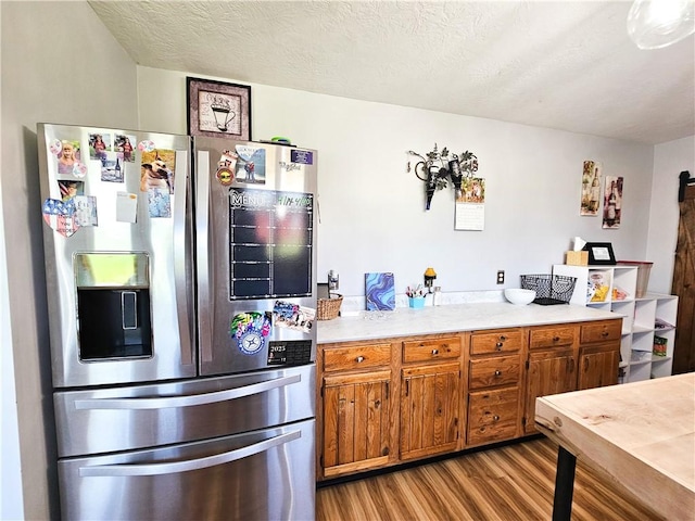 kitchen with brown cabinets, stainless steel refrigerator with ice dispenser, wood finished floors, and light countertops