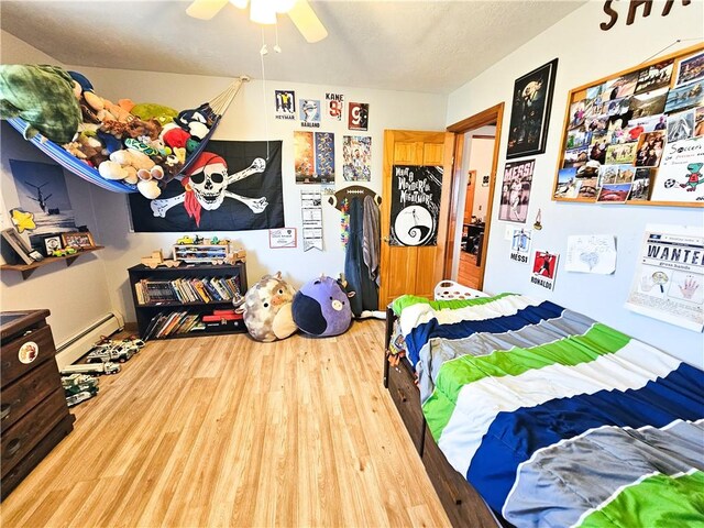 bedroom featuring a baseboard radiator, wood finished floors, and a ceiling fan