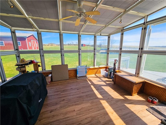 sunroom / solarium with a healthy amount of sunlight, a ceiling fan, and rail lighting