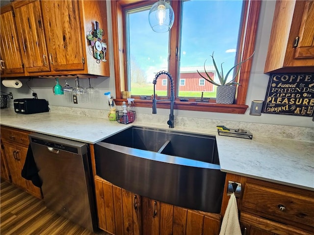kitchen with brown cabinetry, stainless steel dishwasher, light countertops, and a sink