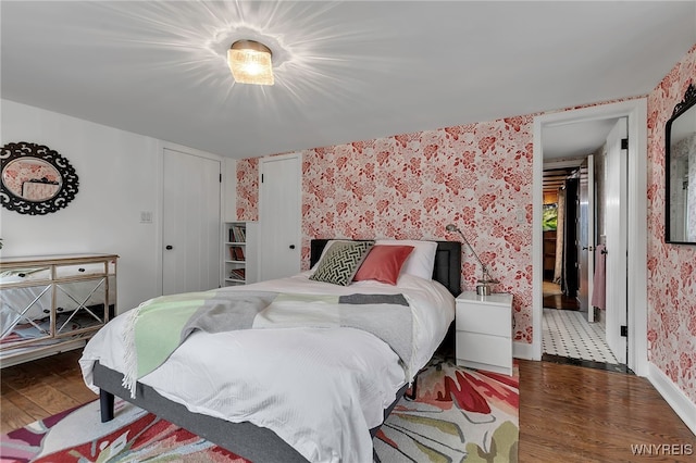 bedroom with wallpapered walls and wood finished floors