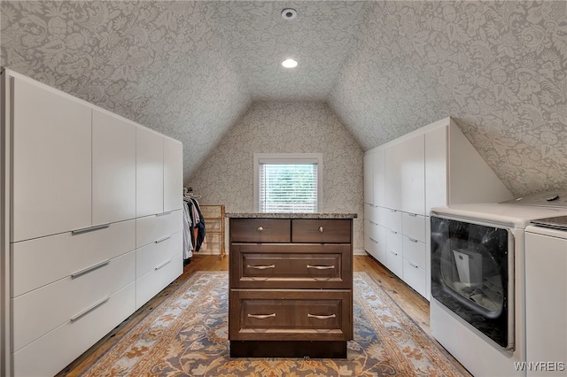 spacious closet with wood finished floors, washing machine and clothes dryer, and vaulted ceiling