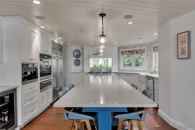 kitchen featuring beverage cooler, light countertops, and a sink