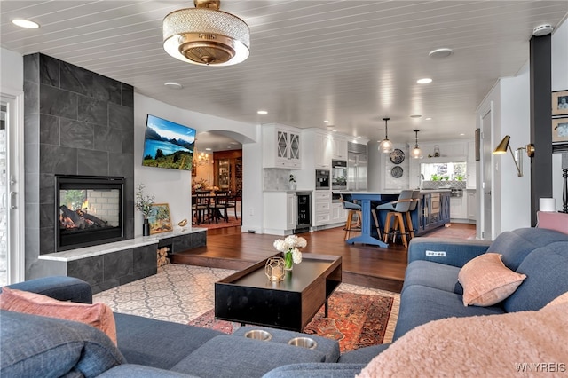 living area featuring recessed lighting, wood finished floors, arched walkways, and wine cooler