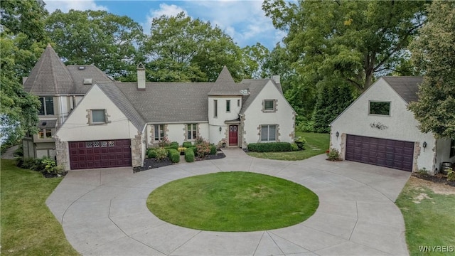 view of front of property featuring stucco siding, a chimney, a front yard, and a garage