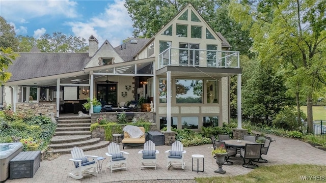rear view of house featuring stairs, a balcony, a patio area, roof with shingles, and stucco siding