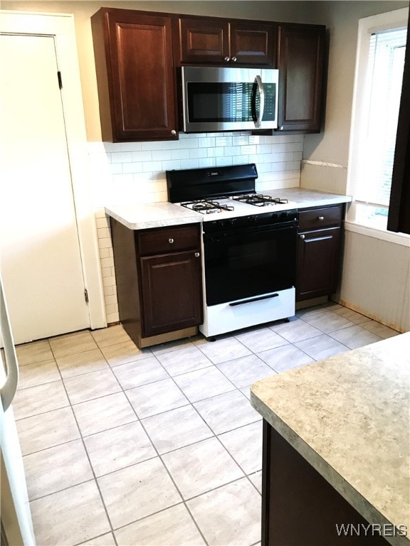 kitchen featuring gas stove, tasteful backsplash, light countertops, and stainless steel microwave