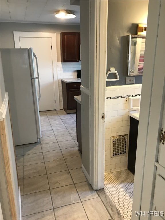 hallway with light tile patterned floors, visible vents, and wainscoting