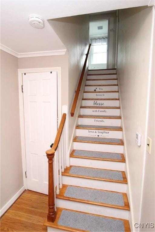 staircase featuring crown molding, baseboards, and wood finished floors