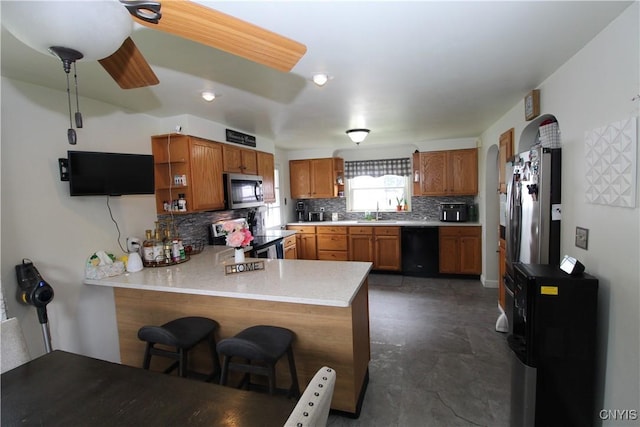 kitchen featuring a sink, light countertops, stainless steel appliances, a peninsula, and backsplash