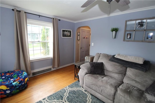living area with visible vents, a ceiling fan, ornamental molding, wood finished floors, and arched walkways